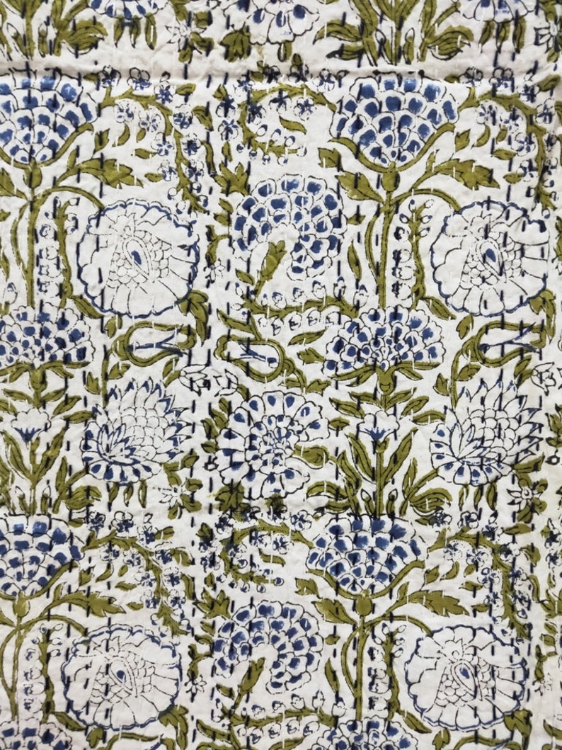 May include: A white fabric with a repeating pattern of blue and green flowers. The flowers are stylized and have a vintage look.
