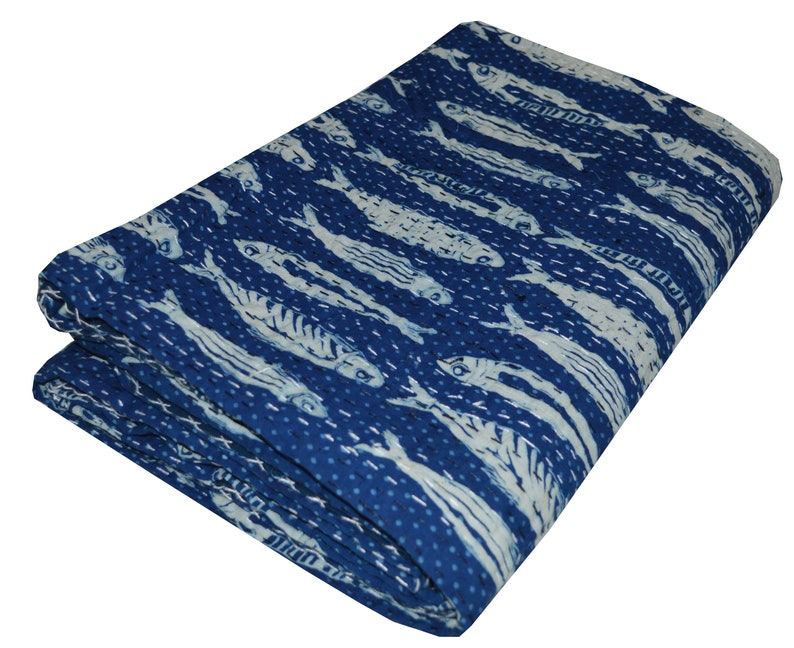 May include: A blue kantha quilt with a white fish pattern. The quilt is folded and has a textured surface.