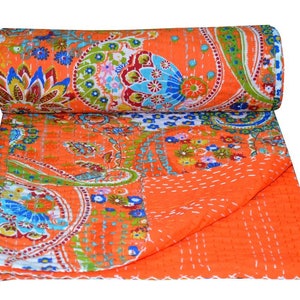 Puede incluir: Colcha kantha naranja con estampado paisley y detalles florales. La colcha est&aacute; doblada por la mitad y enrollada.