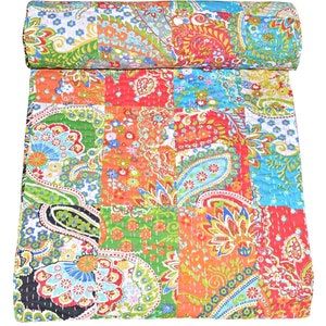 Puede incluir: Una colcha de retazos colorida con un patr&oacute;n de paisley. La colcha est&aacute; hecha de varias telas en tonos de rojo, naranja, verde, azul y blanco. La colcha est&aacute; doblada por la mitad y est&aacute; sobre un fondo blanco.