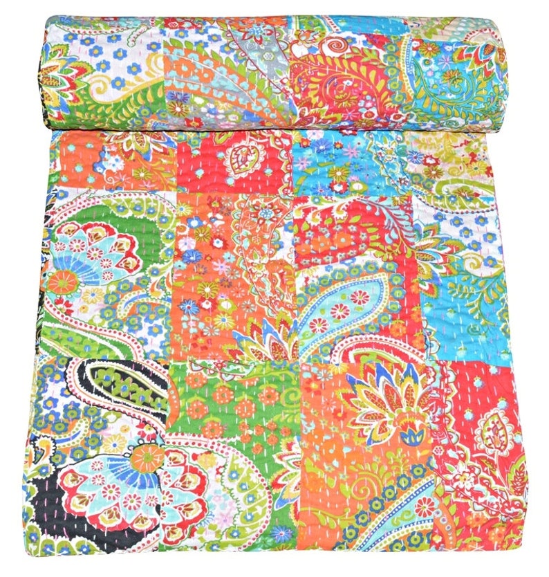 Puede incluir: Una colcha de retazos colorida con un patr&oacute;n de paisley. La colcha est&aacute; hecha de varias telas en tonos de rojo, naranja, verde, azul y blanco. La colcha est&aacute; doblada por la mitad y est&aacute; sobre un fondo blanco.