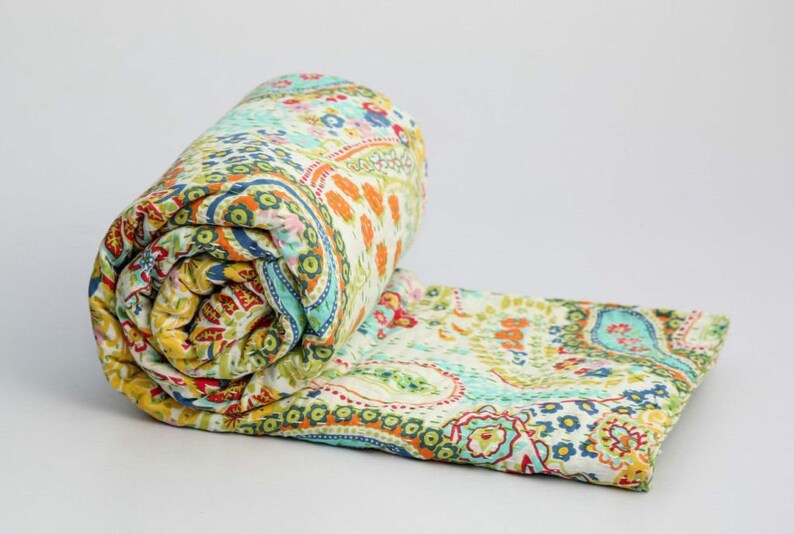 Puede incluir: Una colcha enrollada con estampado paisley en tonos verdes, azules, amarillos, naranjas y rojos. La colcha est&aacute; hecha de algod&oacute;n y es perfecta para a&ntilde;adir un toque de estilo bohemio a cualquier habitaci&oacute;n.