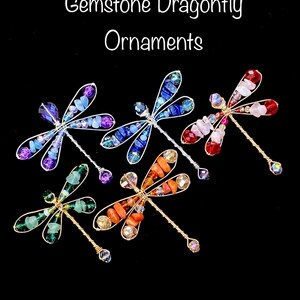 May include: Five gemstone dragonfly ornaments. Each dragonfly is made of wire and has a different color gemstone body. The colors are blue, red, green, orange, and purple.