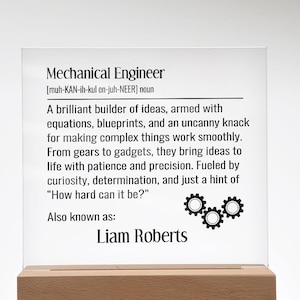 May include: A clear acrylic plaque with the definition of "Mechanical Engineer" printed in black. The plaque is mounted on a rectangular wooden base. The text includes a pronunciation guide, a description, and the name "Liam Roberts".