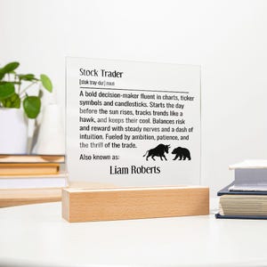 May include: A clear acrylic sign with the definition of "Stock Trader" printed in black. The sign is mounted on a light wood base. The text includes the name "Liam Roberts".