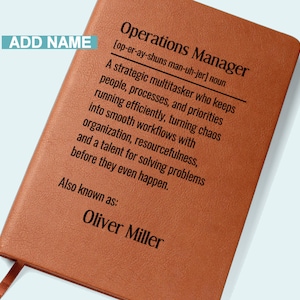 May include: A brown leather notebook with the text "Operations Manager" and a definition. The name "Oliver Miller" is printed below the definition. A ribbon bookmark is visible.