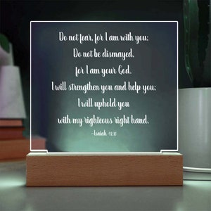 May include: A white acrylic plaque with a wood base, displaying a bible verse from Isaiah 41:10. The verse reads: "Do not fear, for I am with you; Do not be dismayed, for I am your God. I will strengthen you and help you: I will uphold you with my righteous right hand."