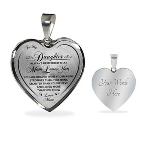 Pode incluir: Colar com pingente de cora&ccedil;&atilde;o prateado com uma mensagem para uma filha. O lado da frente diz "To My Daughter Always Remember That Mom Loves You You Are Braver Than You Imagine Stronger Than You Think Smarter Than You Believe And Loved More Than You Know Love Mom". O lado de tr&aacute;s est&aacute; em branco e diz "Your Words Here".