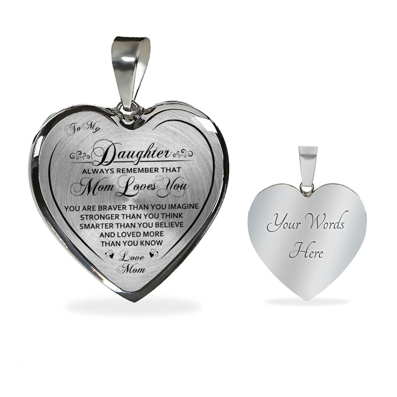 Pode incluir: Colar com pingente de cora&ccedil;&atilde;o prateado com uma mensagem para uma filha. O lado da frente diz "To My Daughter Always Remember That Mom Loves You You Are Braver Than You Imagine Stronger Than You Think Smarter Than You Believe And Loved More Than You Know Love Mom". O lado de tr&aacute;s est&aacute; em branco e diz "Your Words Here".