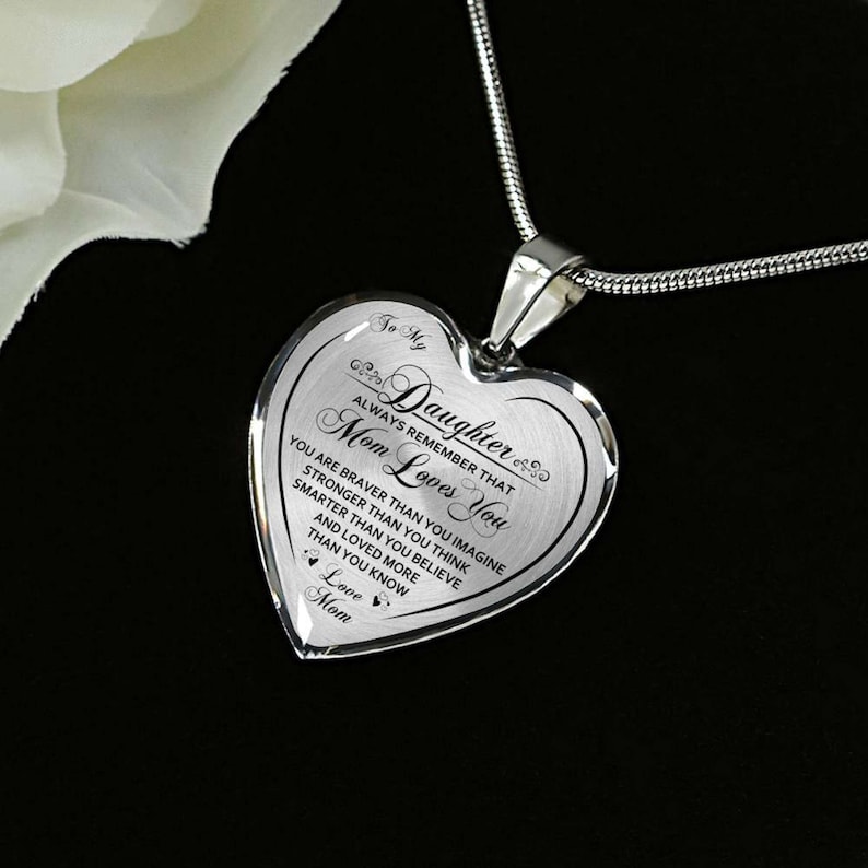 Pode incluir: Colar de prata em forma de cora&ccedil;&atilde;o com uma mensagem que diz "To My Daughter Always Remember That Mom Loves You You Are Braver Than You Imagine Stronger Than You Think Smarter Than You Believe And Loved More Than You Know Love Mom".