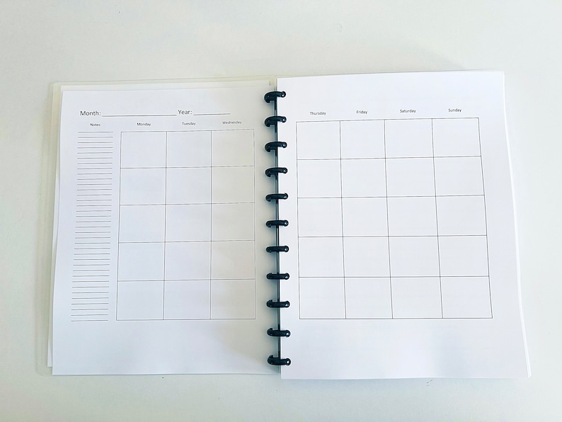 May include: A white planner with a black coil binding. The left page has a section for notes and a monthly calendar grid. The right page has a weekly calendar grid with days of the week labeled: Thursday, Friday, Saturday, Sunday.