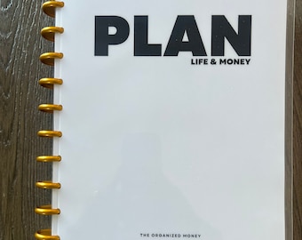 Puede incluir: Una agenda blanca con una encuadernación en espiral dorada. La portada tiene la palabra "PLAN" en letras negras en negrita y el texto "LIFE & MONEY" en letras negras más pequeñas debajo. La parte inferior de la portada tiene el texto "THE ORGANIZED MONEY" en letras negras.