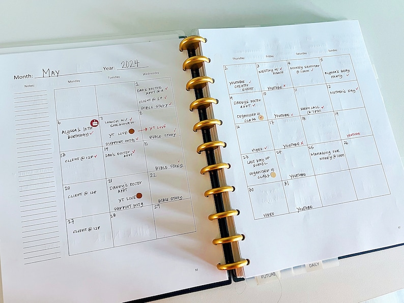 May include: A monthly planner with a white background and black grid lines. The month of May is highlighted with the year 2024. The planner has a gold and black ring binder. The planner has a section for future and daily.