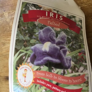 May include: A craft kit to felt a purple iris flower. The kit includes yarn, a pattern, and stem wire. The packaging features a cartoon girl holding knitting needles and the text "Another knit kit by Pick Up Sticks!" and "From bulb to bloom in hours!"