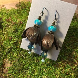 May include: A pair of earrings with a bronze flower design, blue and white glass beads, and crystal accents.