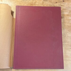 May include: A burgundy hardback book with a plain cover.