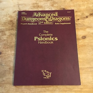 May include: A burgundy book cover with gold lettering. The title is "Advanced Dungeons & Dragons" with the subtitle "The Complete Psionics Handbook". The book is a rules supplement for the 2nd edition of the game.