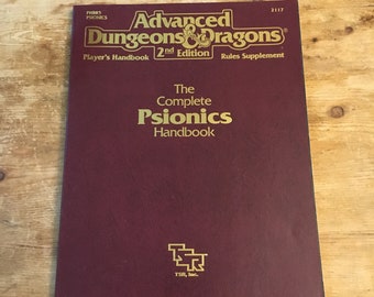 May include: A burgundy book cover with gold lettering. The title is "Advanced Dungeons & Dragons" with the subtitle "The Complete Psionics Handbook". The book is a rules supplement for the 2nd edition of the game.