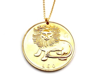 May include: Gold necklace with a round pendant featuring a detailed lion design and the word "LEO" inscribed below.