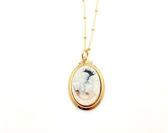 May include: Gold chain necklace with a gold oval pendant featuring a cameo of two women's faces with the word "GEMINI" and the dates "MAY 21 - JUNE 21" around the cameo.