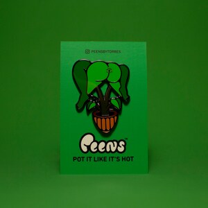 May include: A green enamel pin featuring a stylized plant in a brown pot. The pin is on a green card with the text "Peens" and "POT IT LIKE IT'S HOT". The Instagram handle "PEENSBYTORRES" is also visible.