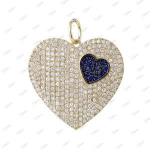 May include: A gold-toned heart pendant encrusted with small, clear gemstones. A smaller heart, filled with dark blue gemstones, is set within the larger heart. The pendant has a small loop at the top for a chain.