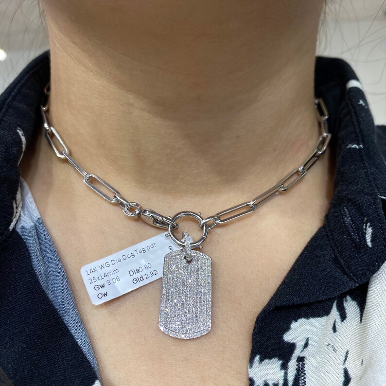May include: A silver chain necklace with a silver dog tag pendant encrusted with small diamonds. The tag is 2.5x1.4 cm and the chain is 3.08 grams. The tag has 0.80 carats of diamonds and weighs 2.92 grams.