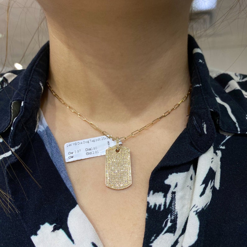 May include: A gold chain necklace with a diamond-encrusted dog tag pendant. The tag is rectangular and has a polished finish. The tag is labeled "14k YG Dia Dog Tag pat 25.11" and "Gw 2.97 Dia.80 Gld 2.81".