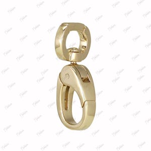 May include: A gold-toned metal swivel lobster clasp featuring a smooth, polished finish. The hardware consists of a circular top loop connected to a spring-loaded trigger mechanism that opens and closes to secure items, showcasing a sleek design.