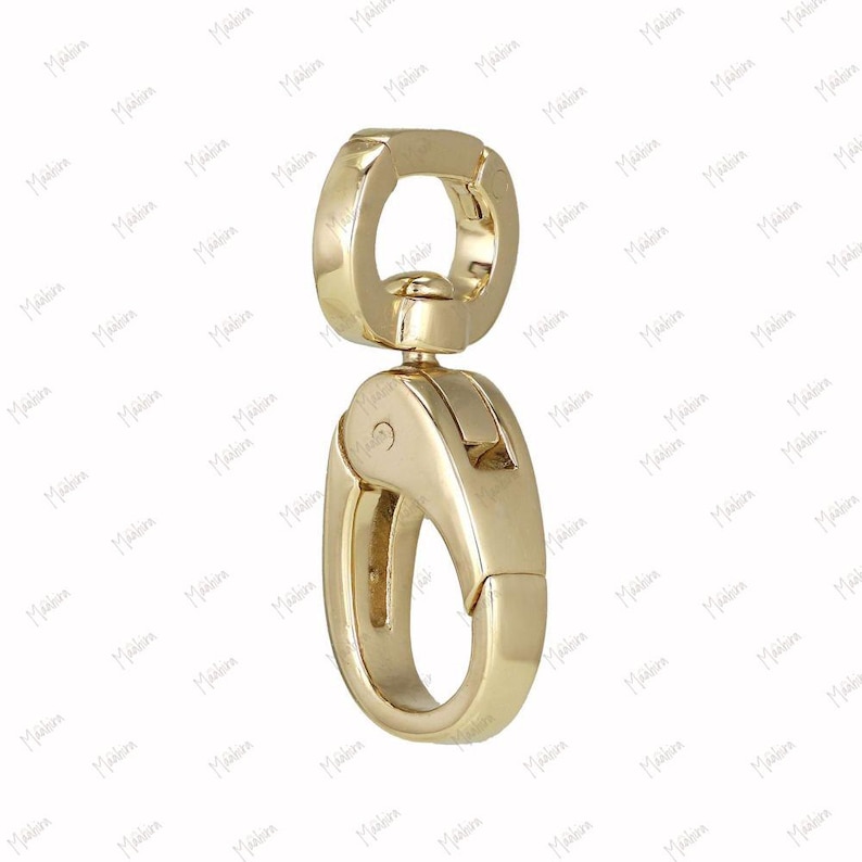 May include: A gold-toned metal swivel lobster clasp featuring a smooth, polished finish. The hardware consists of a circular top loop connected to a spring-loaded trigger mechanism that opens and closes to secure items, showcasing a sleek design.