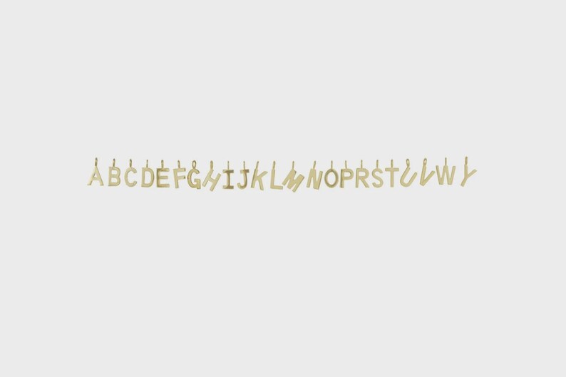 May include: A collection of gold-colored metal letter charms arranged in a horizontal line. Each individual letter pendant features a small loop at the top for attachment, showcasing a simple, clean font style with a polished metallic finish.