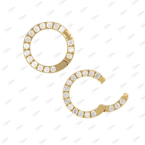 May include: Two gold hoop earrings with a circle of small clear stones around the edge.