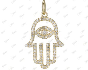 May include: A gold Hamsa hand pendant featuring a central eye motif, entirely encrusted with small, clear pavé-set stones. The openwork design includes a small circular bail at the top for attachment to a chain, showcasing a metallic finish.