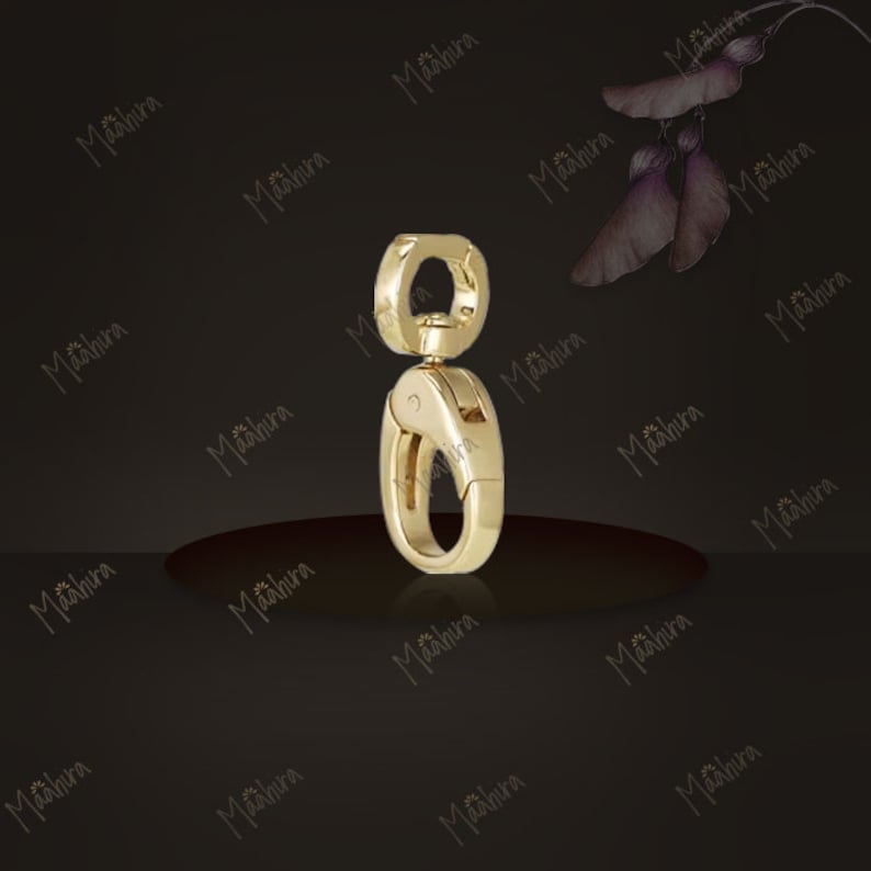 May include: A gold-toned metal swivel lobster clasp featuring a smooth, polished finish. The hardware consists of a circular top loop connected to a spring-loaded oval hook mechanism designed for secure attachment to various items or accessories.