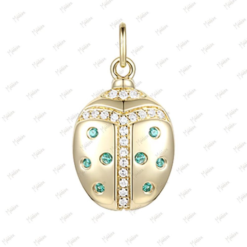 May include: A gold-tone charm in the shape of a ladybug with green and white accents. The charm is adorned with small, clear cubic zirconia stones.