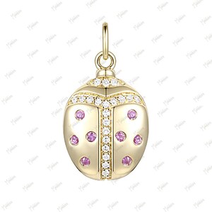 May include: A gold charm in the shape of a ladybug with pink and white stones.