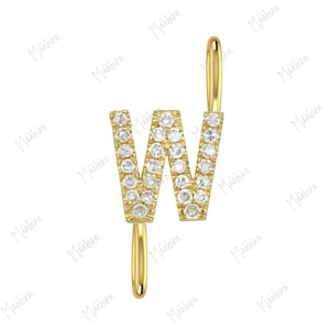 May include: A gold letter W pendant featuring a series of small, clear, round-cut stones embedded along the surface of the letter. The pendant includes a smooth, curved gold bail at the top and a matching gold loop extending from the bottom.