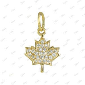 May include: A gold maple leaf pendant featuring a series of small, clear, round-cut stones embedded across the surface of the leaf. The pendant includes a circular gold bail at the top for attachment to a chain, showcasing a detailed design.