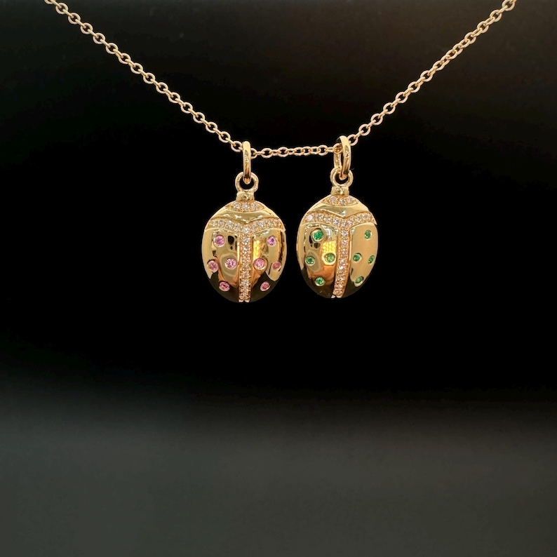 May include: Two gold ladybug pendants with diamond accents. One ladybug has pink and white stones, the other has green and white stones.