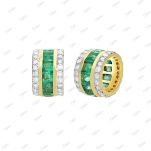 May include: A pair of gold hoop earrings with emerald green and white gemstones. The earrings are set in a gold band and feature a row of emerald green gemstones surrounded by white gemstones.