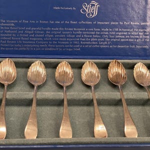 May include: A set of six silver teaspoons with a fluted bowl design, presented in a blue box. Each spoon is approximately 12.7 cm long. The box is labelled "Made Exclusively By Stieff."