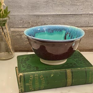 Puede incluir: Juego de tres tazas de cerámica con acabado mate moteado. Las tazas son de color crema, gris claro y gris oscuro. Cada taza tiene un diseño simple y minimalista.