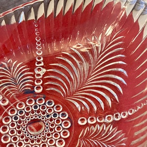 May include: A clear glass bowl with a decorative etched design of leaves and circles. The bowl has a scalloped edge and is perfect for serving fruit or snacks.