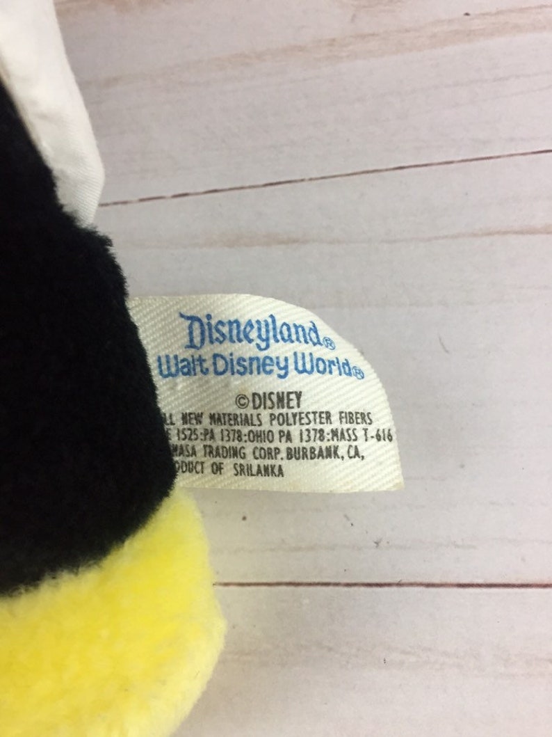 May include: Black and yellow plush bee toy with a white wing. The tag reads "Disneyland Walt Disney World &copy;DISNEY All New Materials Polyester Fibres 1525:PA 1378:OHIO PA 1378:MASS T-616 MASA TRADING CORP. BURBANK, CA, PRODUCT OF SRILANKA"