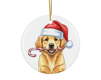 Puede incluir: Adorno navideño redondo y blanco con un Golden Retriever con un gorro de Papá Noel rojo y un bastón de caramelo. El perro tiene una expresión feliz. Una cuerda dorada está unida para colgarlo.