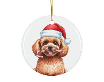 May include: A round Christmas ornament featuring a brown dog wearing a Santa hat and holding a candy cane. The dog has a happy expression. The ornament has a gold string for hanging and is set against a white background.