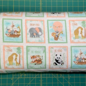 May include: White fabric roll with repeating square patterns featuring cute animal illustrations. Each square has a different animal, such as a panda, elephant, giraffe, and tiger, with inspirational phrases like "Be Kind" and "Dream Big".