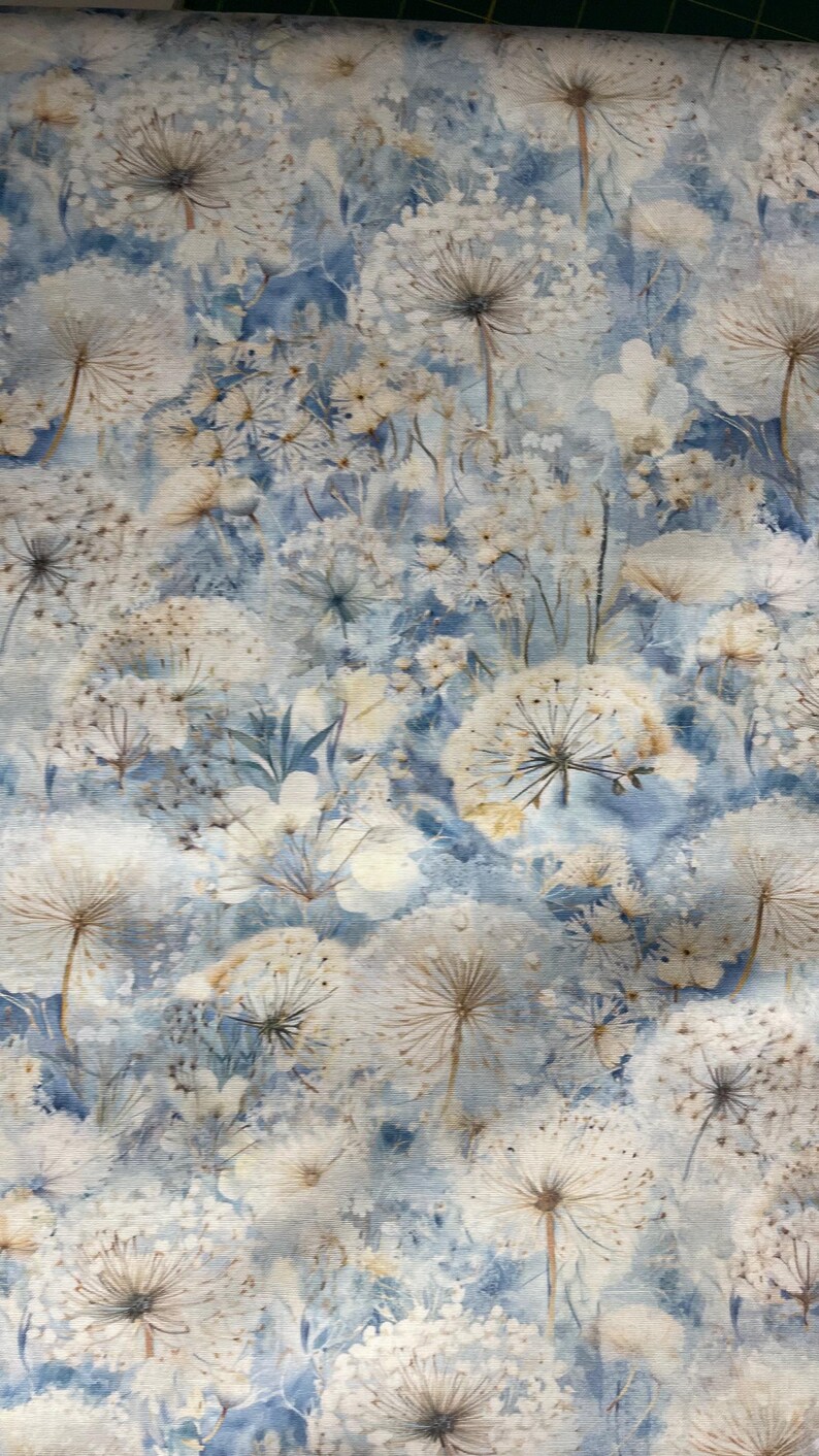 以下が含まれることがあります： 白いタンポポの種子頭と、淡い青色の水彩画の背景に繊細な白い花が描かれた、花柄の生地。 デザインは柔らかく、夢のような美しさで、さまざまなクラフトプロジェクトに適しています。