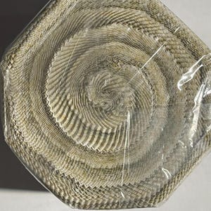 May include: A roll of beige and white fabric ribbon with a textured, woven pattern. The ribbon is wrapped in clear plastic.