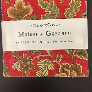 May include: A stack of fabric squares with a red background and a floral pattern in shades of brown, green, and tan. The fabric is labeled "Maison de Garance" by French General for Moda.